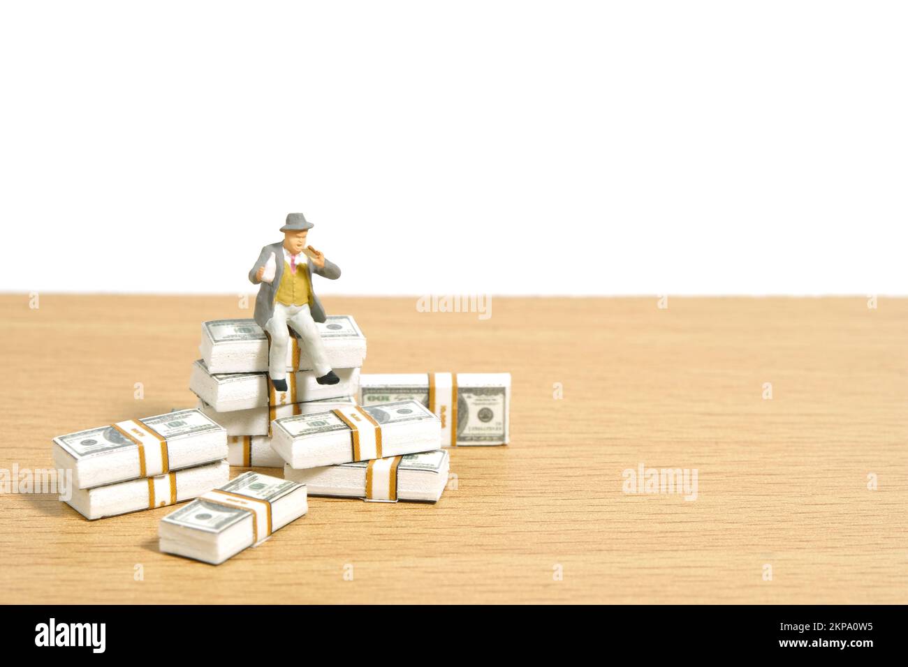 Miniatur-Menschen-Spielzeug-Figuren-Fotografie. Pensions- und Rentenkonzept. Männer Arbeiter, die über Banknoten auf einem Schreibtisch stapeln. Bildfoto Stockfoto