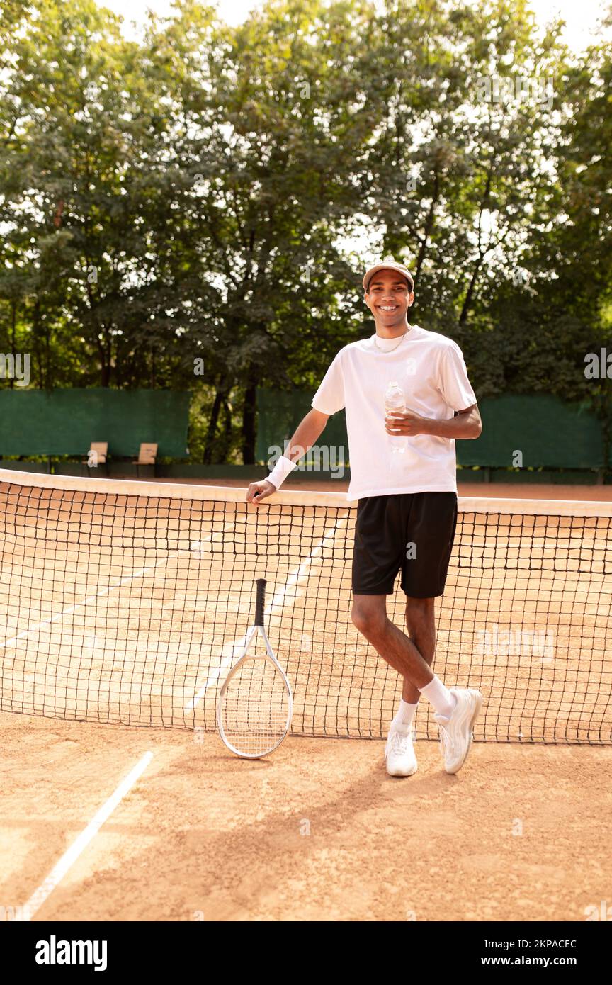 Ein junger Mann im weißen Thirt, der am Tennisplatz steht Stockfoto