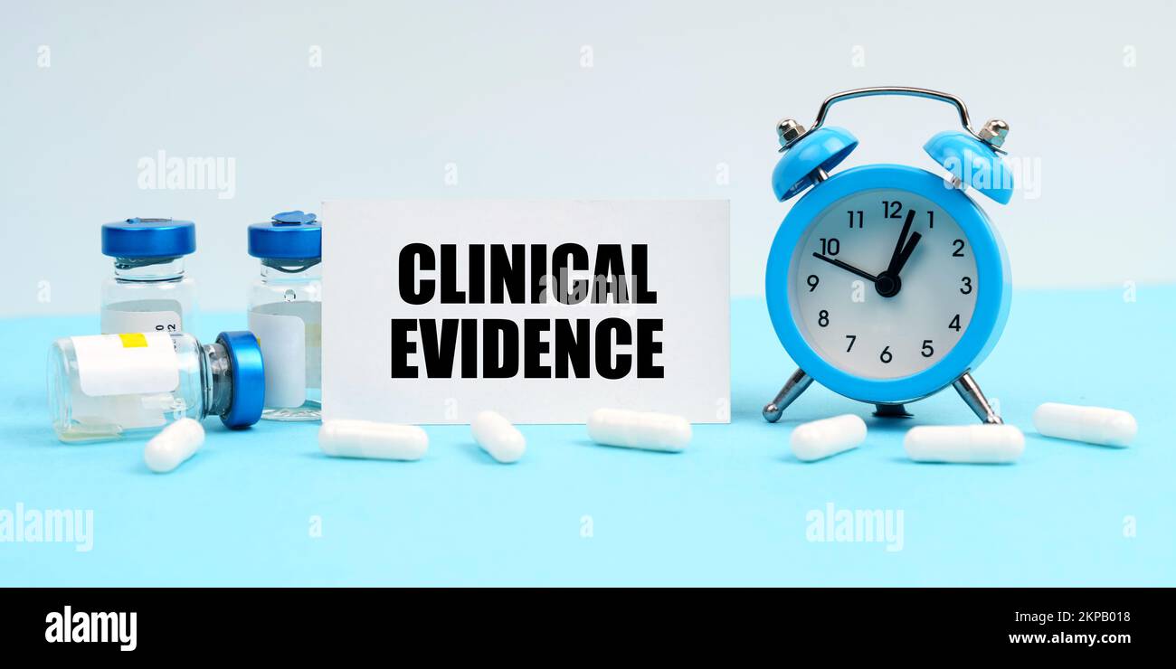 Medizin und Gesundheitskonzept. Wecker, Pillen, Injektionen und eine Karte mit der Inschrift - Klinische Evidenz Stockfoto