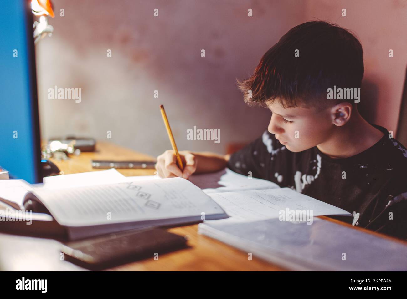 Ein fleißiger, weißer Junge, der abends Hausaufgaben macht Stockfoto