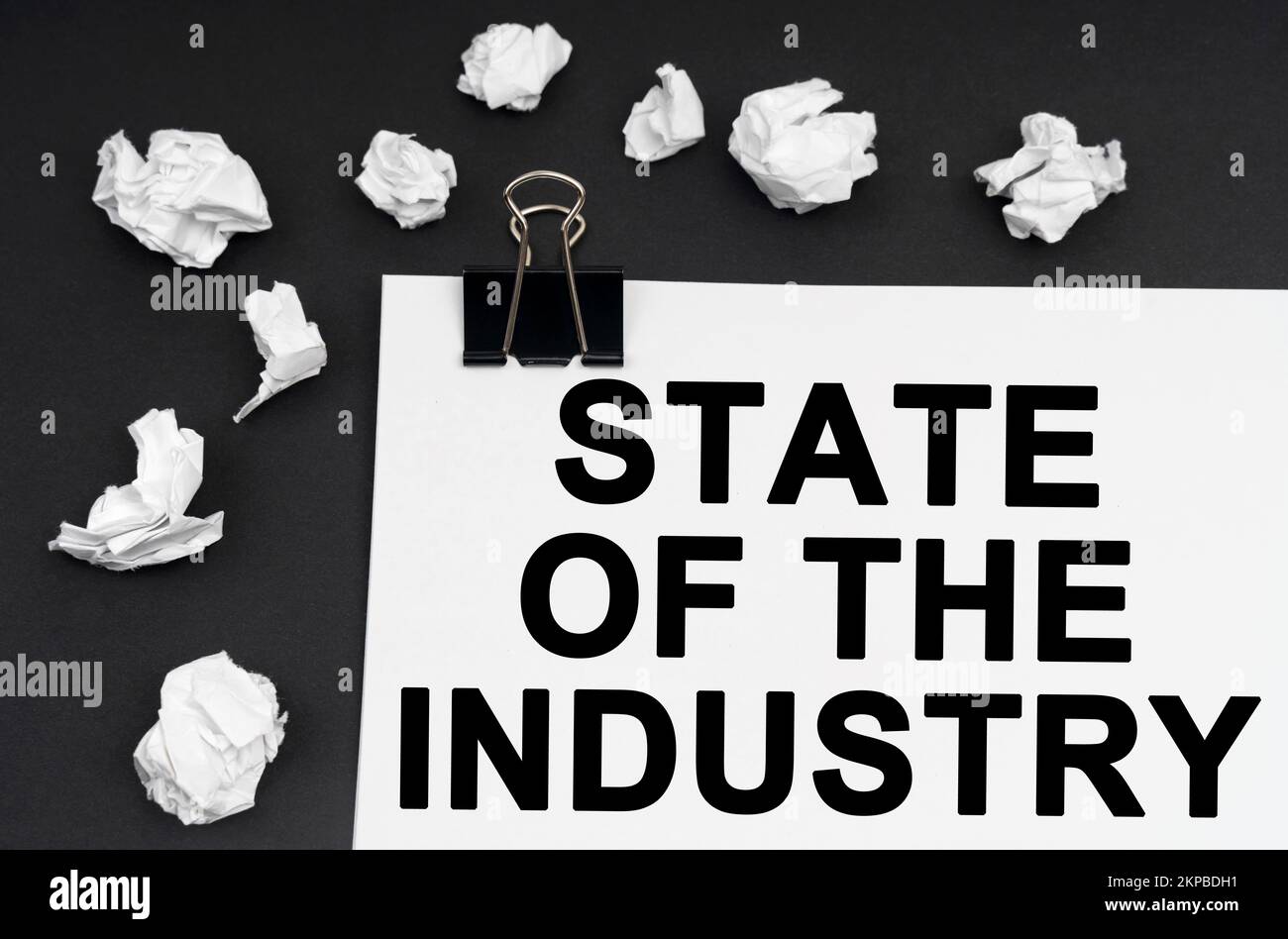 Industriekonzept. Auf schwarzem Hintergrund befinden sich zerknitterte Papierstücke und Papier mit der Aufschrift "STATE OF THE INDUSTRY" Stockfoto