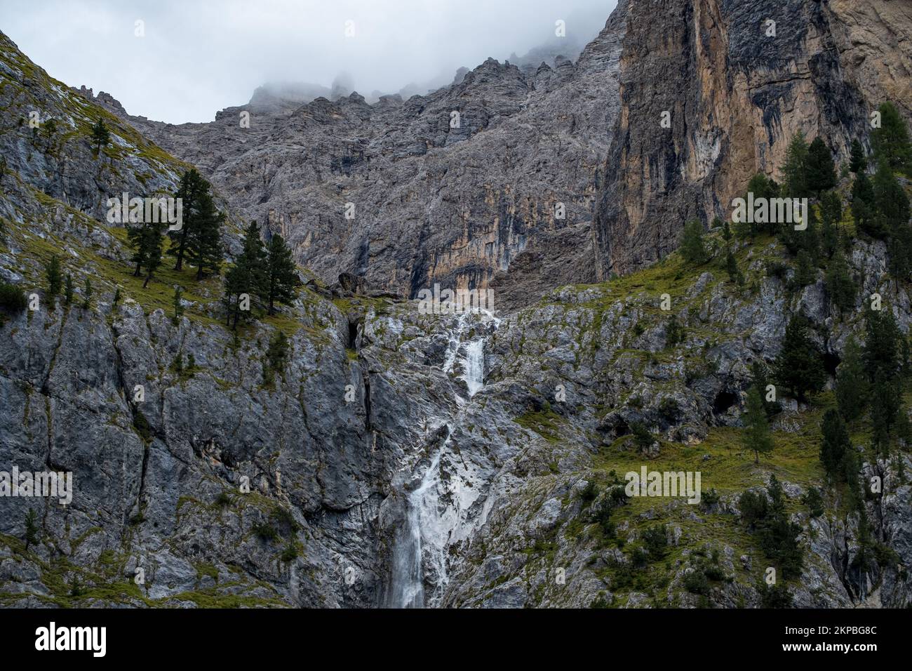 Landschaftsblick mit einem Wasserfall im Berg und grünen Bäumen im Sella Pass, Südtirol Stockfoto
