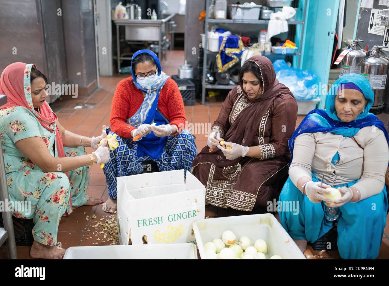 Sikh-Frauen schneiden Ingwer und Zwiebeln, die in einer Langar serviert werden, eine Gemeinschaftsküche in einem Queens Tempel, die kostenloses Essen für alle bietet. Stockfoto