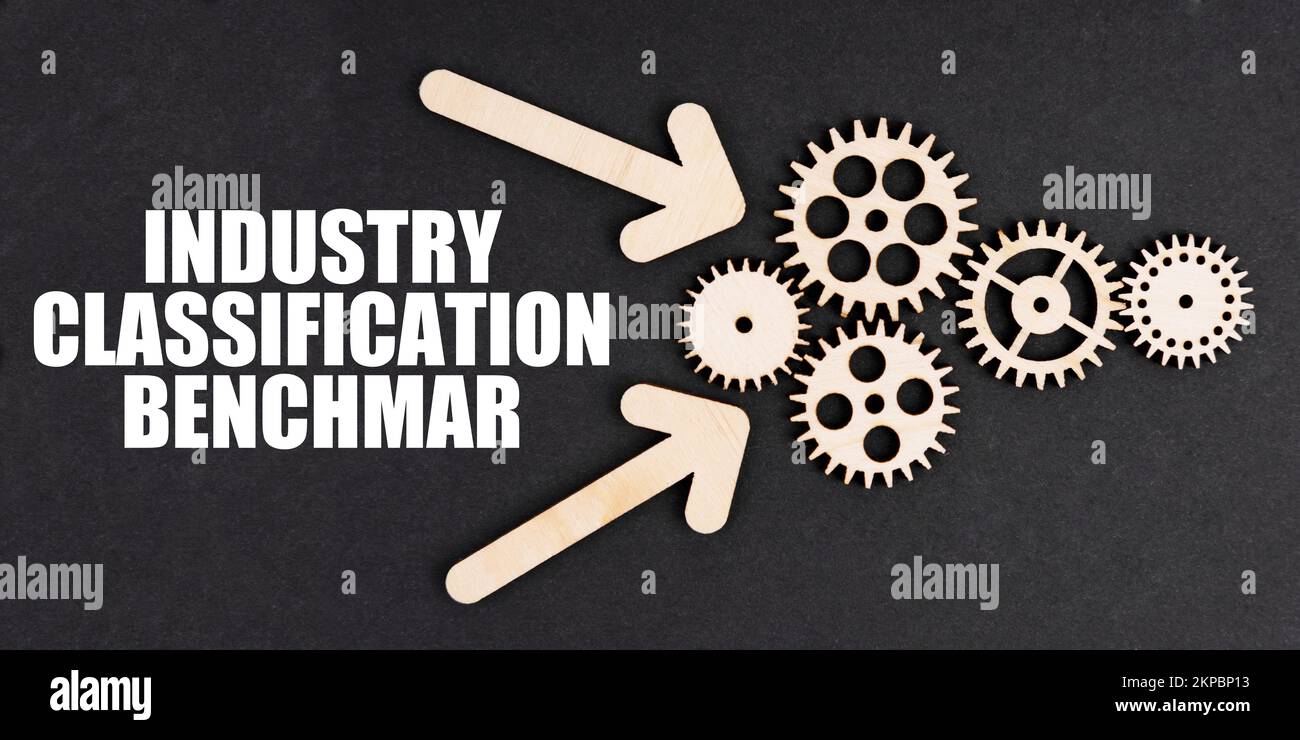 Industriekonzept. Auf der schwarzen Oberfläche befinden sich Pfeile, Zahnräder und eine Aufschrift – Benchmark für die Branchenklassifizierung Stockfoto