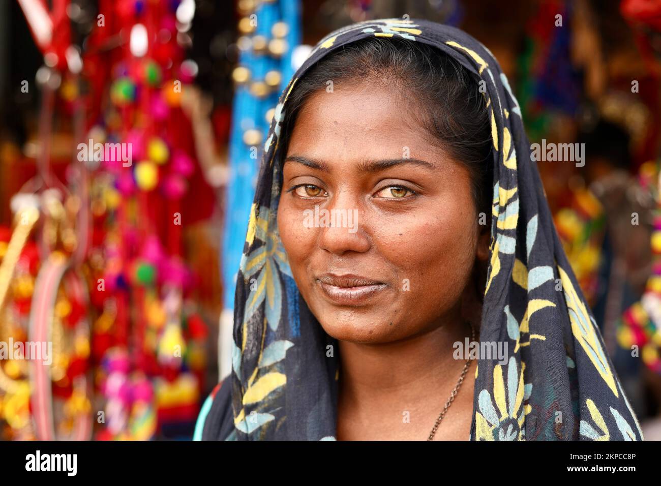 Ein Porträt eines lächelnden indischen Kalbelia-Stammesjungen Mädchens mit grünen und gelben Augen Stockfoto