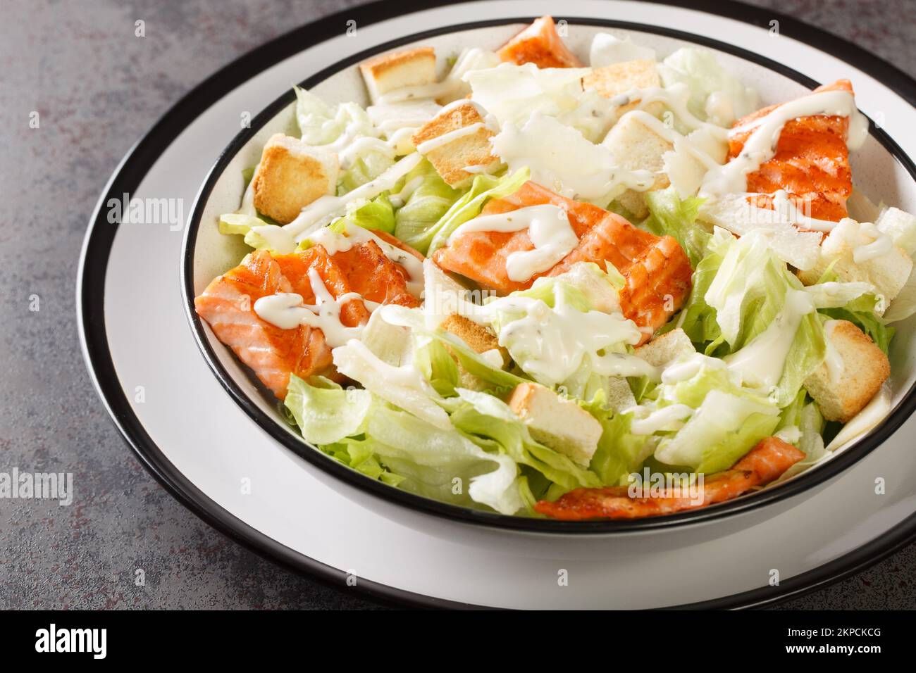 Teller mit frischem caesar-Salat mit gegrilltem Lachs, Croutons, Parmesan, Cäsar-Dressing-Nahtaufnahme auf dem Teller auf dem Tisch. Horizontal Stockfoto