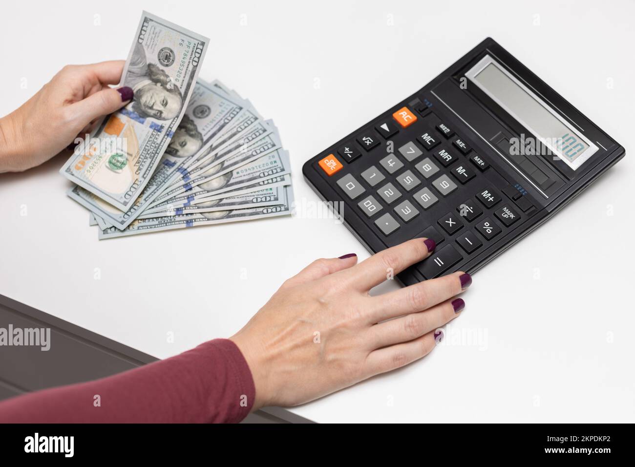 Mann, der Dollars zählt. Frau verteilt das Haushaltsbudget. Kassenbuchhaltung. Fingerdruck auf die Rechnertaste. Stockfoto