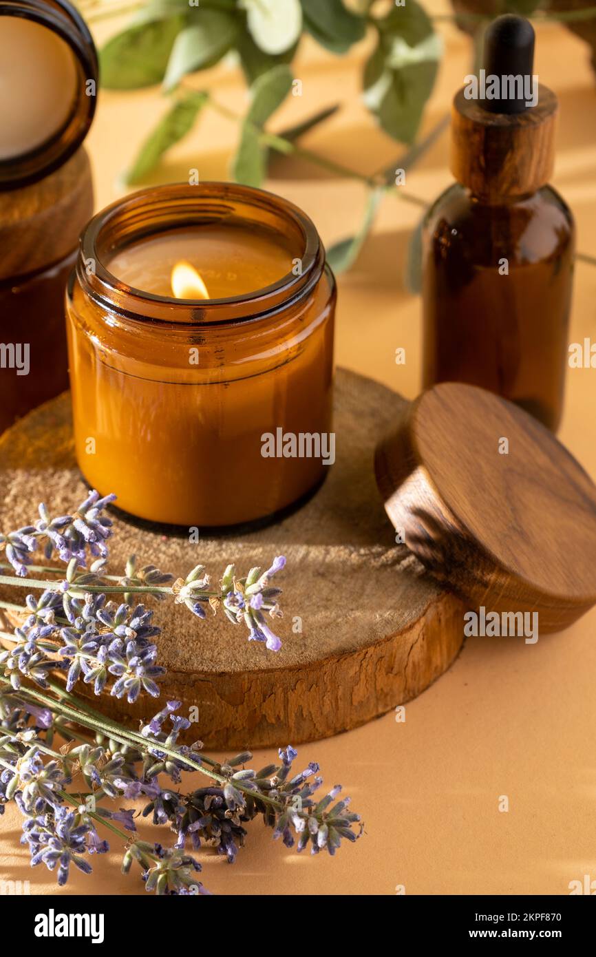 Sojalkerzen in einem Glas. Aromatherapie. Brennende Kerze und Lavendel. Deckel aus Holz für Gläser. Beigefarbener Hintergrund. Komfort und Entspannung. Handgefertigt. Inneneinrichtung. Stockfoto