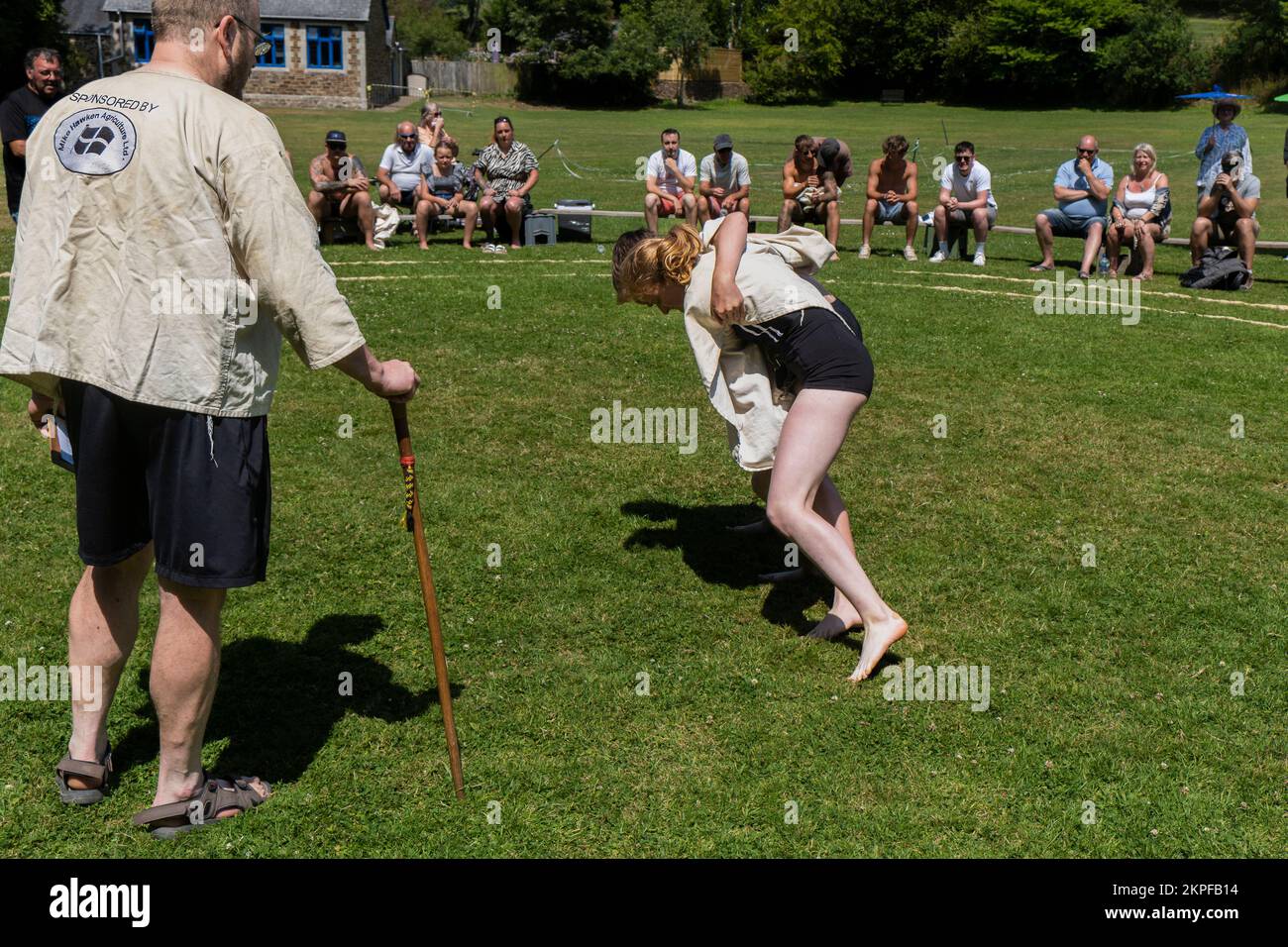 Ein Schiedsrichter Stickler beobachtet ein junges Mädchen im Teenageralter beim Grand Cornish Wrestling Tournament in St. Mawgan in Pydar beim Ringen mit einem Jungen Stockfoto