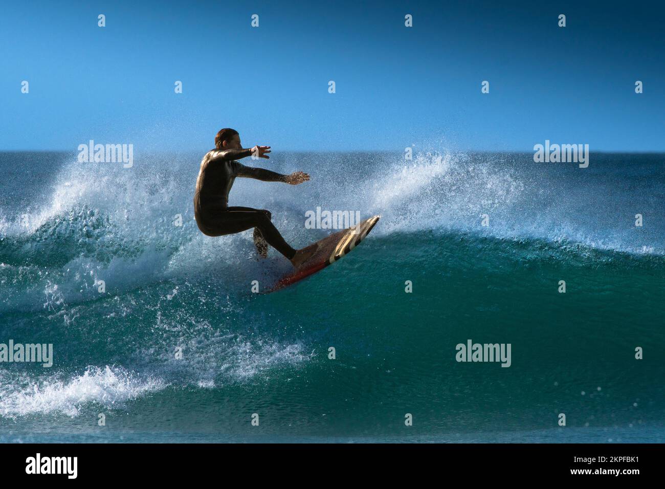 Spektakuläre Surfaktion als männlicher Surfer reitet auf einer Welle im Fistral in Newquay in Cornwall in England in Großbritannien. Stockfoto
