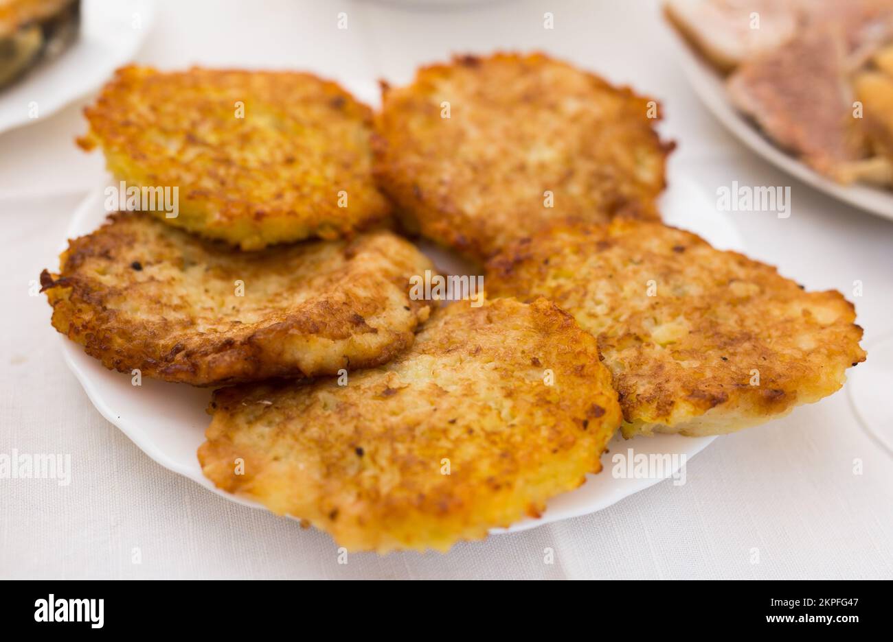 Gebratene Kartoffelpfannkuchen mit Sauerrahm auf weißem Teller ...