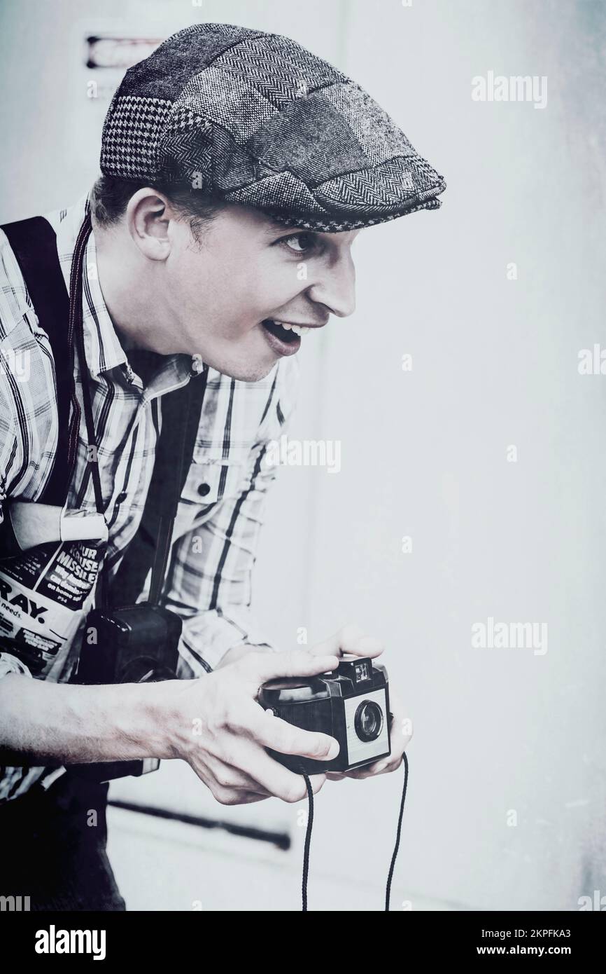 Uraltes blaues Foto eines alten lächelnden Fotografen, der den Auslöser auf die Kamera der 50er Jahre klickt. Erinnerungen aus der Vergangenheit festhalten Stockfoto