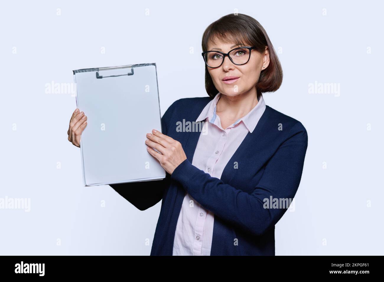 Geschäftsfrau zeigt auf leeren Raum, hält Klemmbrett, weißer Hintergrund Stockfoto