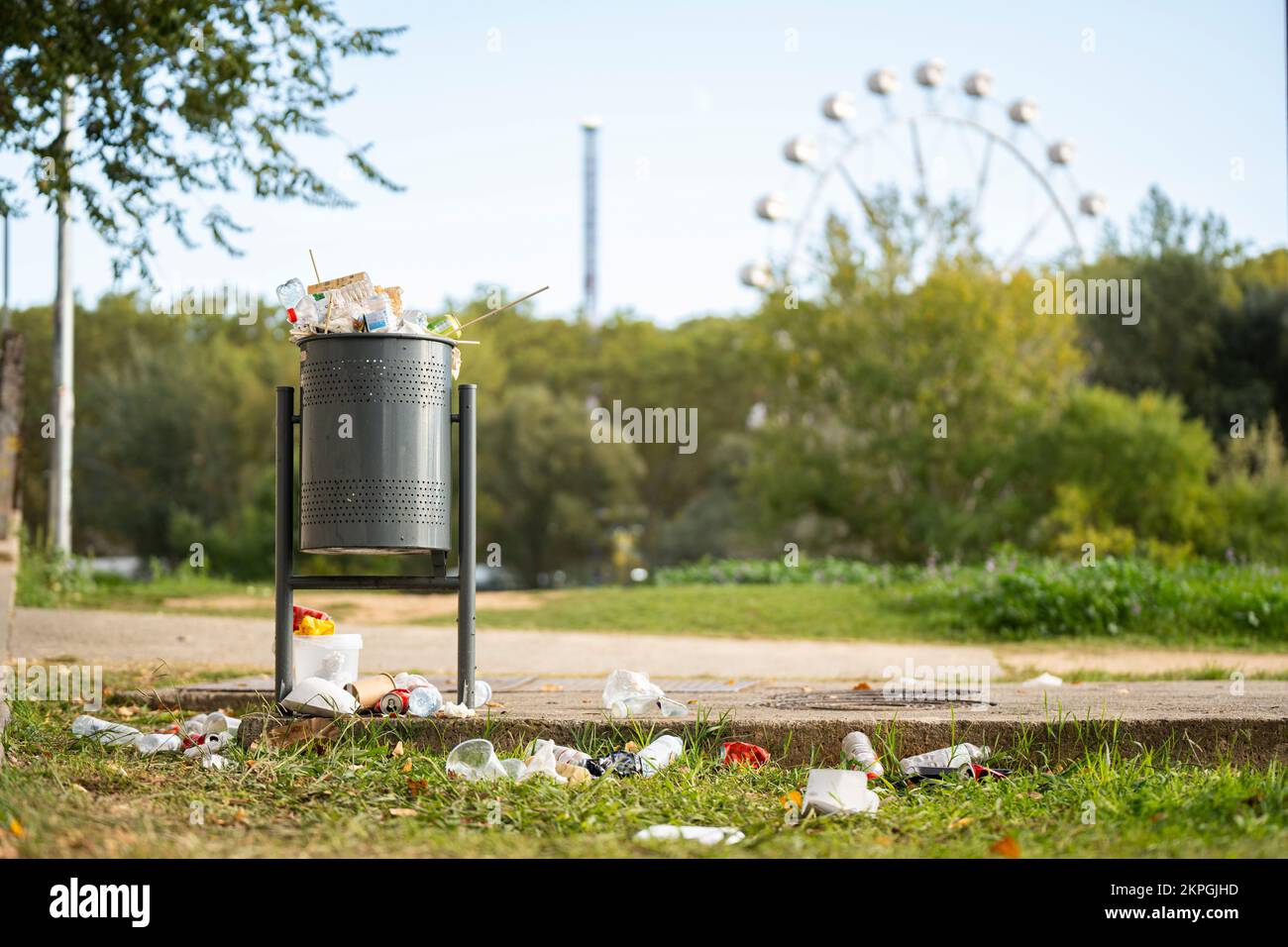 Die Landschaft eines Parks mit einer Mülltonne voller Müll Stockfoto