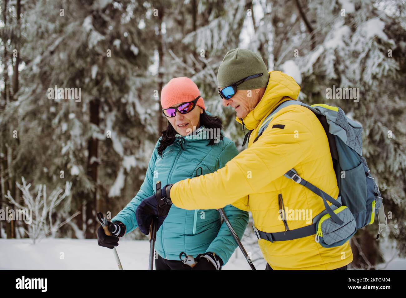 Seniorenpaar, das beim Skifahren auf Smartwatch schaut. Stockfoto
