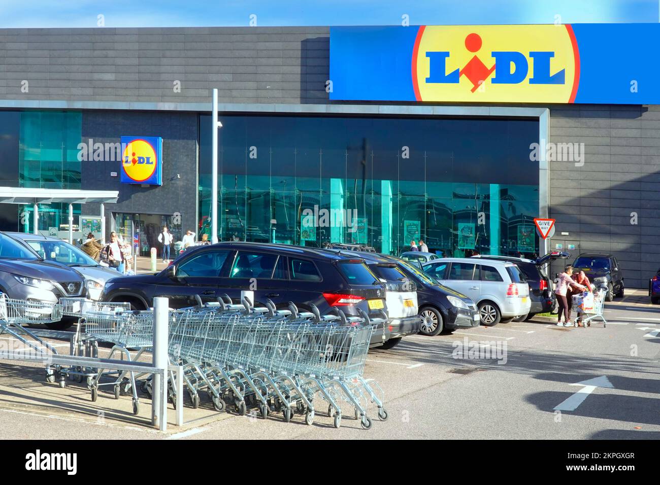 Lidl eröffnet einen neuen Supermarkt in bestehenden Räumlichkeiten, kostenlose Parkplätze für Einkäufer vor den Leuten, die von einem Trolley im Essex Retail Park UK beladen werden Stockfoto