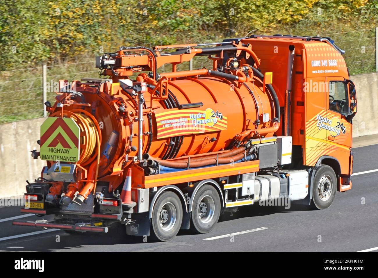 Orangefarbener Lkw-Fahrer in Fahrerkabine mit Tankaufbau für Hydro Cleansing Waste Management & Umweltlösungen auf der britischen Autobahn Stockfoto