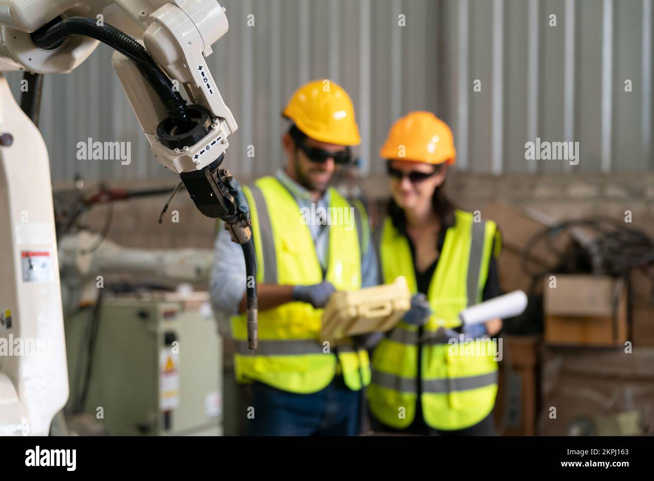Robotikingenieur, der an der Wartung des modernen Roboterarms im Fabriklager arbeitet Stockfoto