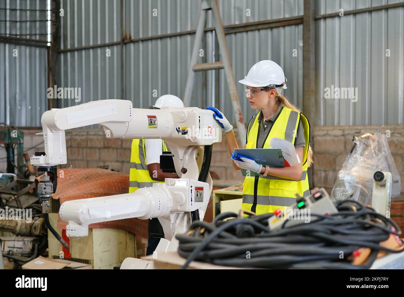 Robotikingenieur, der an der Wartung des modernen Roboterarms im Fabriklager arbeitet Stockfoto