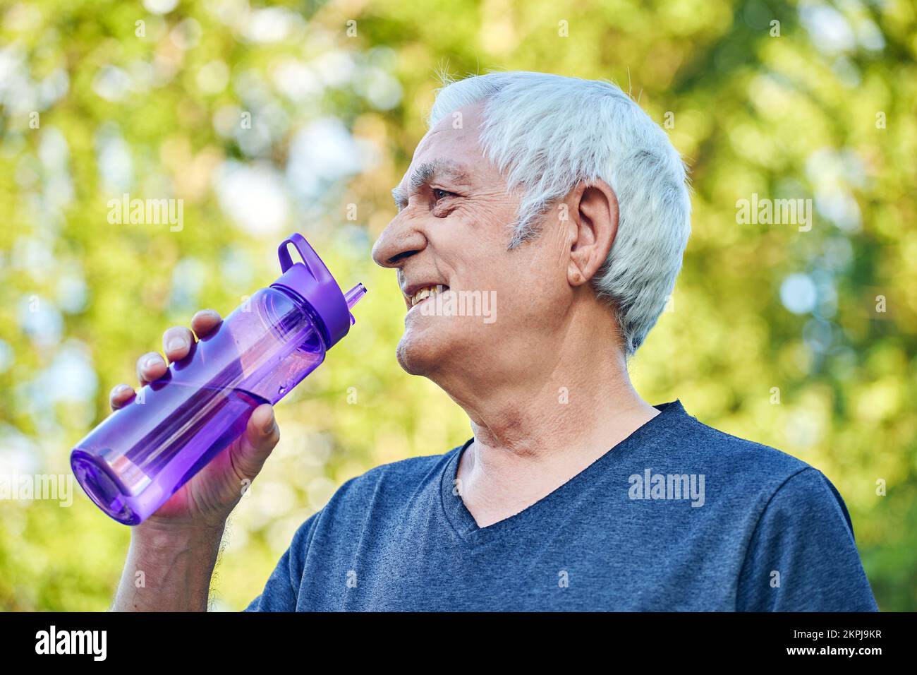 Reifer Mann hält wiederverwendbare Plastikflasche trinkt stilles Mineralwasser während des Morgentrainings oder Spaziergangs im Sommerpark, sich um die Gesundheit kümmern, entlastet Stockfoto