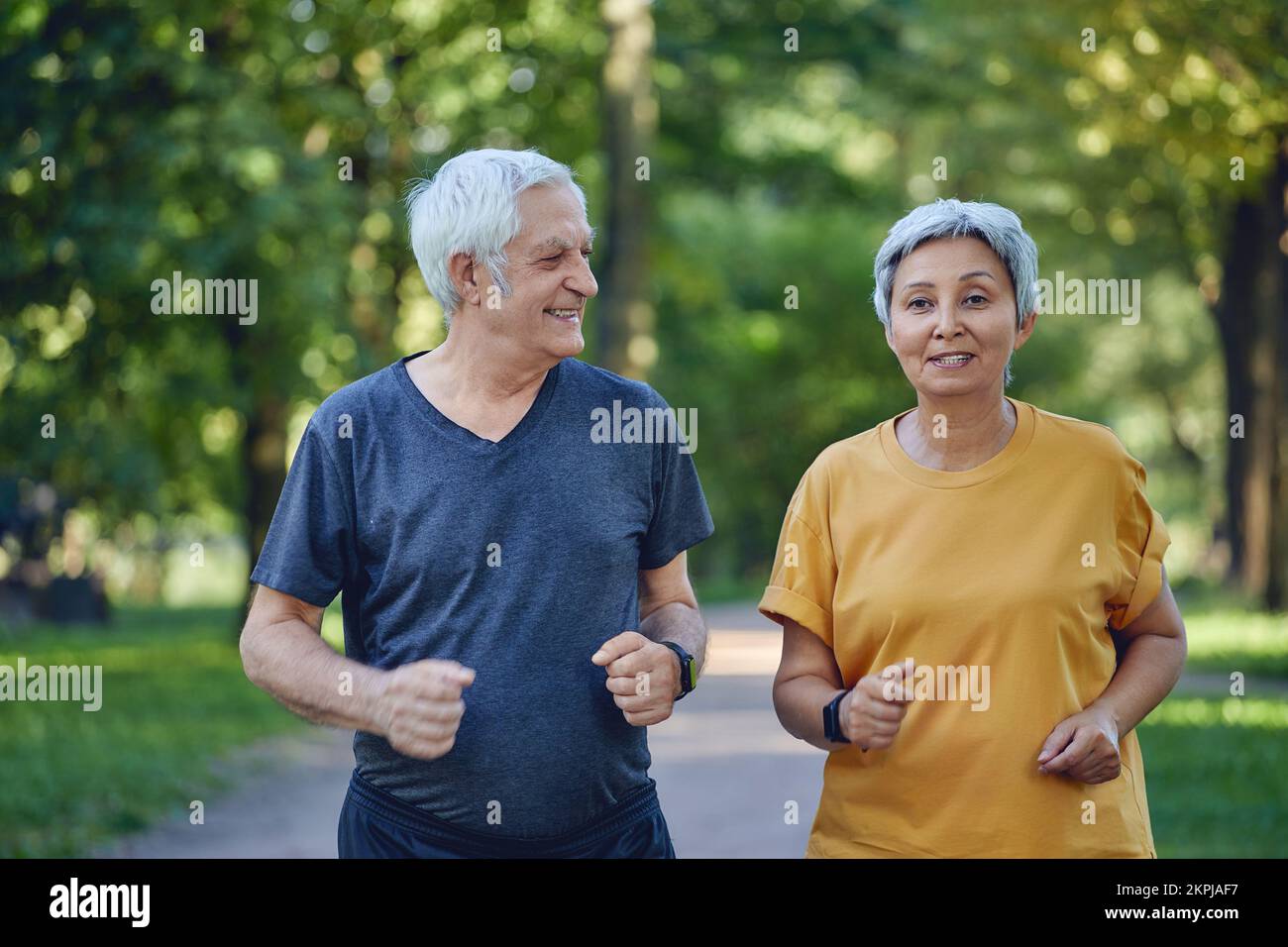 Reifes Paar beim Joggen im Sommerpark. Zwei ältere Jogger genießen morgens aktive Kardio-Aktivitäten im Freien, halten einen gesunden aktiven Lebensstil. Gewichtsverlust, Sport Stockfoto