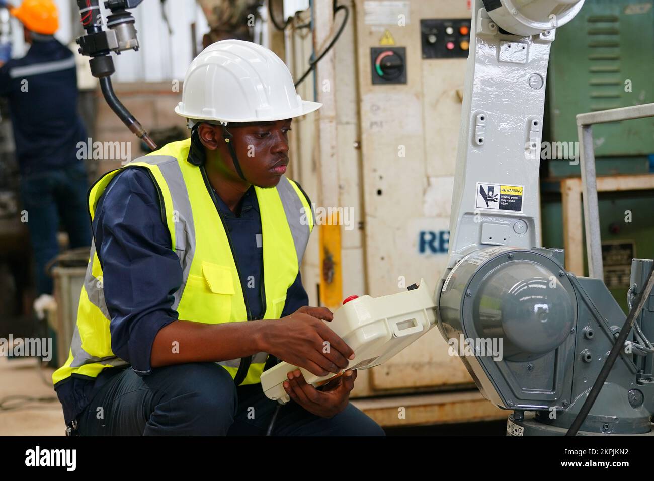 Robotikingenieur, der an der Wartung des modernen Roboterarms im Fabriklager arbeitet Stockfoto
