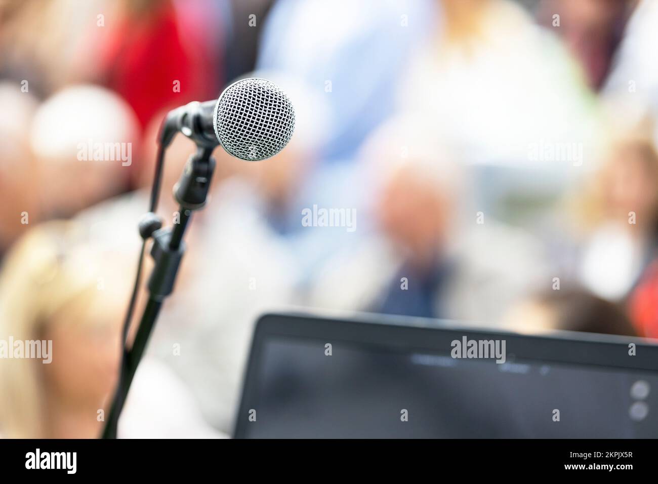 Mikrofon im Fokus gegen verwackelte Publikum. Die Teilnehmer an der geschäftlichen oder beruflichen Konferenz. Stockfoto