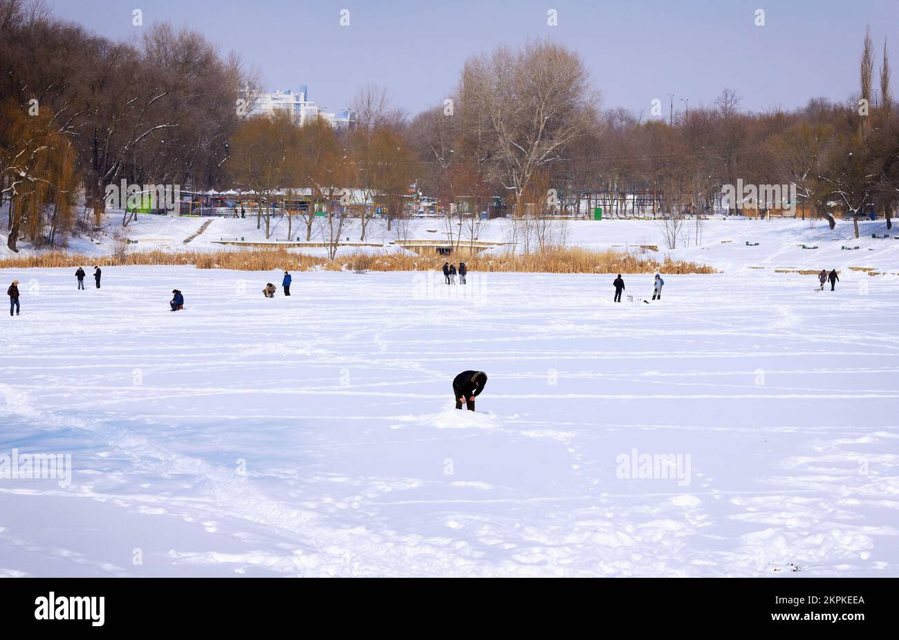 Fischer fischen an einem sonnigen Wintertag auf dem gefrorenen See Stockfoto