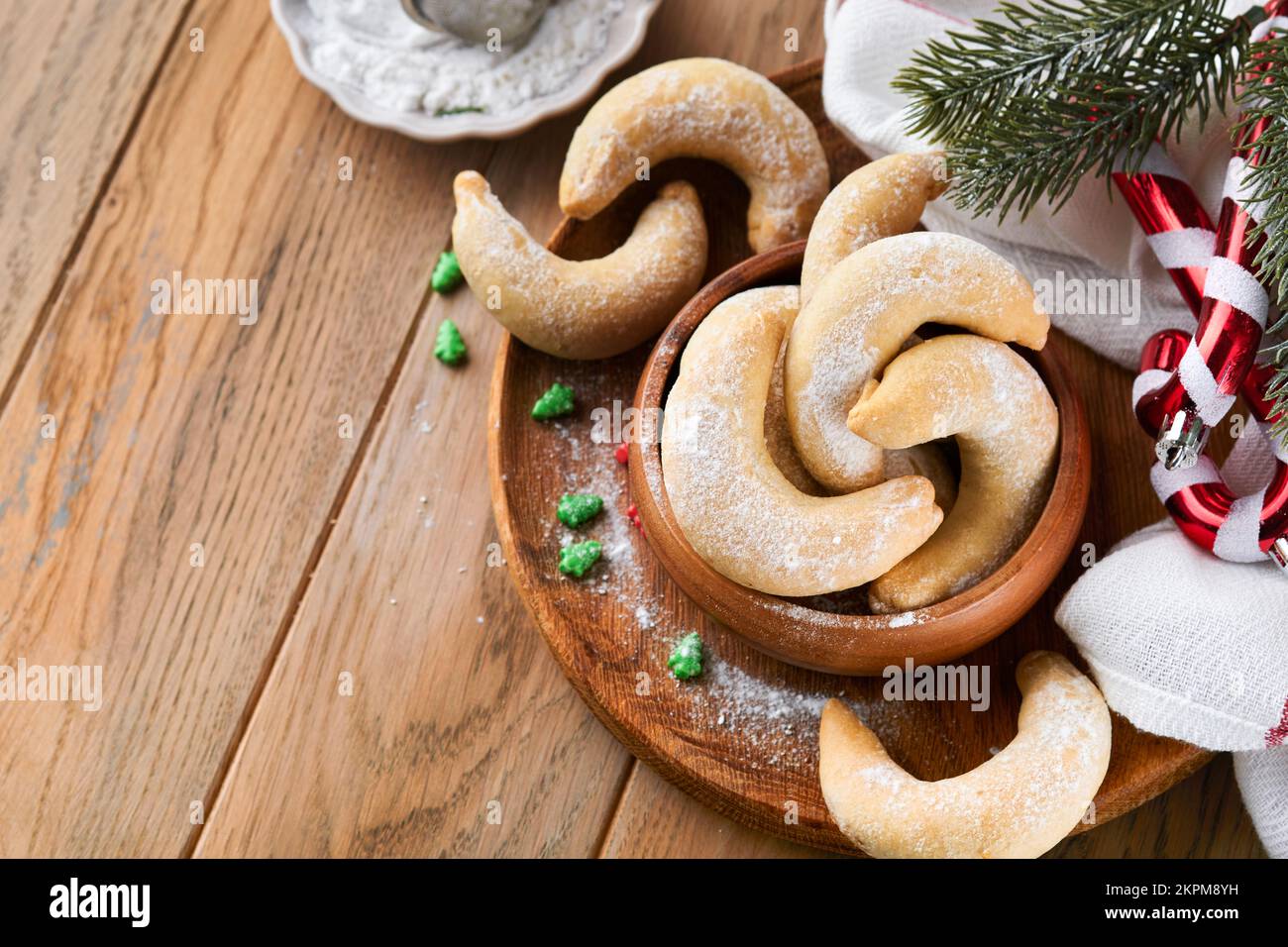 Weihnachtsplätzchen Crescents. Hausgemachte traditionelle Weihnachtskekse Vanillekies in rustikalem Teller mit weihnachtsdekorationen auf altem Holz rustikal Stockfoto