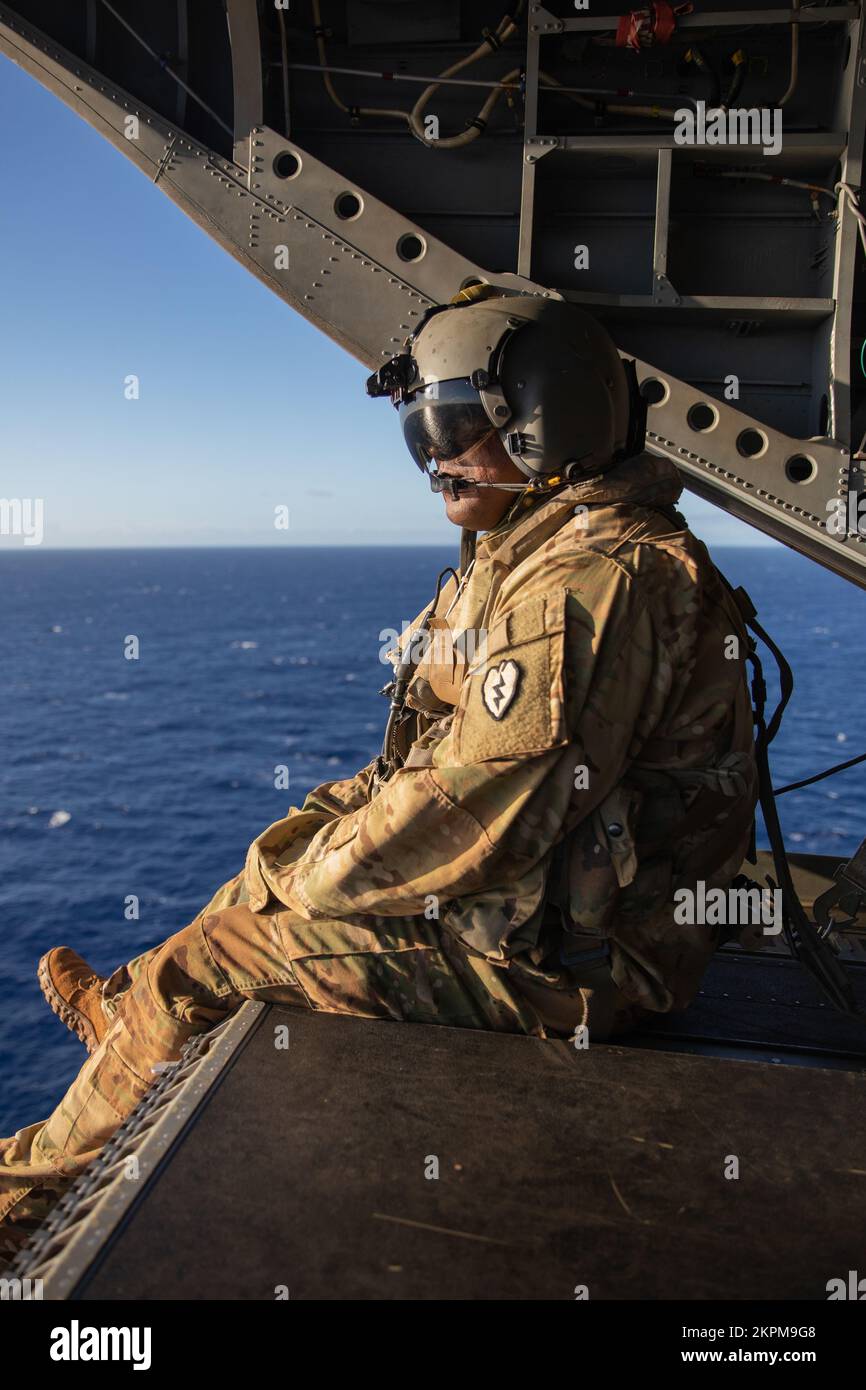USA Army Sgt. Larryel King aus dem 3-25. General Support Aviation Bataillon (GSAB), 25.. Infanteriedivision, blickt auf den Ozean von der Rückseite eines CH-47 Chinook während des Joint Pacific Multinational Readiness Center (JPMRC) Over the Pacific Ocean, Hi., 1. November 2022. King ist Crewchef der GSAB B Co. 3-25 Bergsteiger und hat die Aufgabe, die Sicherheit des Chinook und seiner Passagiere während des JPMRC aufrechtzuerhalten. Stockfoto