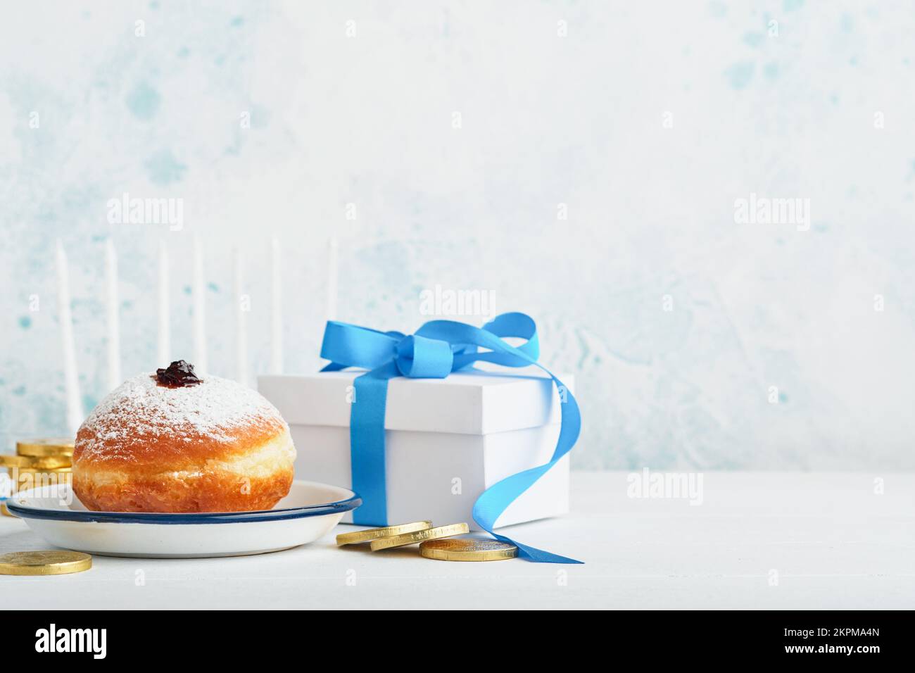 Frohes Chanukka. Süße Hanukka-Donuts, Geschenkschachteln, weiße Kerzen und Schokoladenmünzen auf weißem Holzhintergrund. Bild und Begriff jüdischer Holida Stockfoto