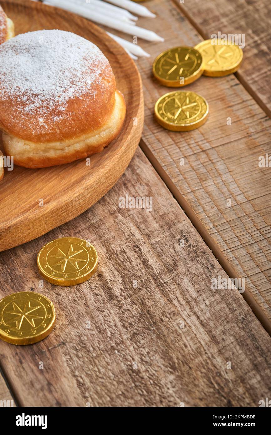 Frohes Chanukka. Süße Hanukka-Donuts, Geschenkschachteln, weiße Kerzen und Schokoladenmünzen auf altem Holzhintergrund. Bild und Konzept des jüdischen Urlaubs Stockfoto