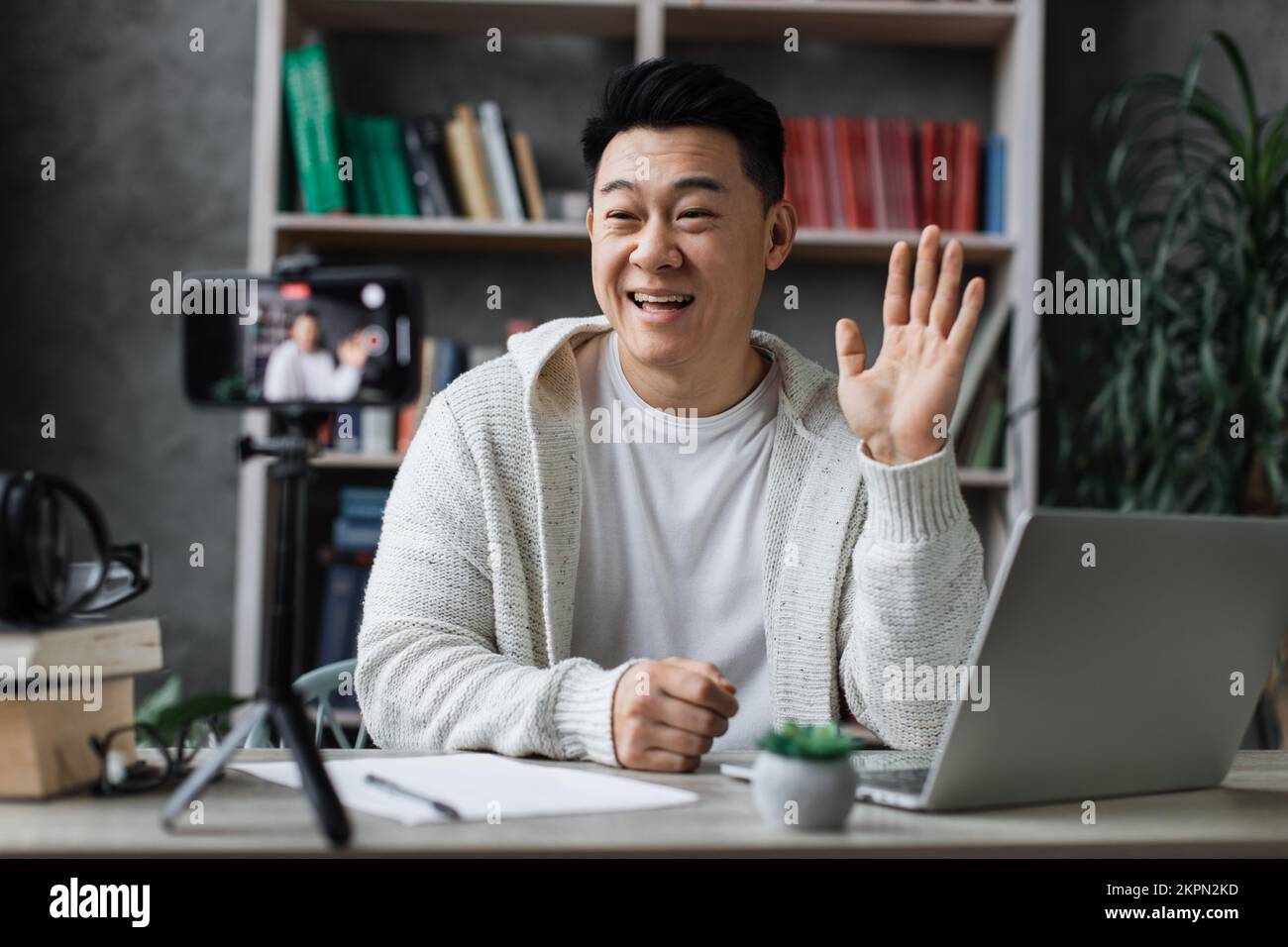 Attraktiver asiatischer Mann in legerer Kleidung, der spricht und ...