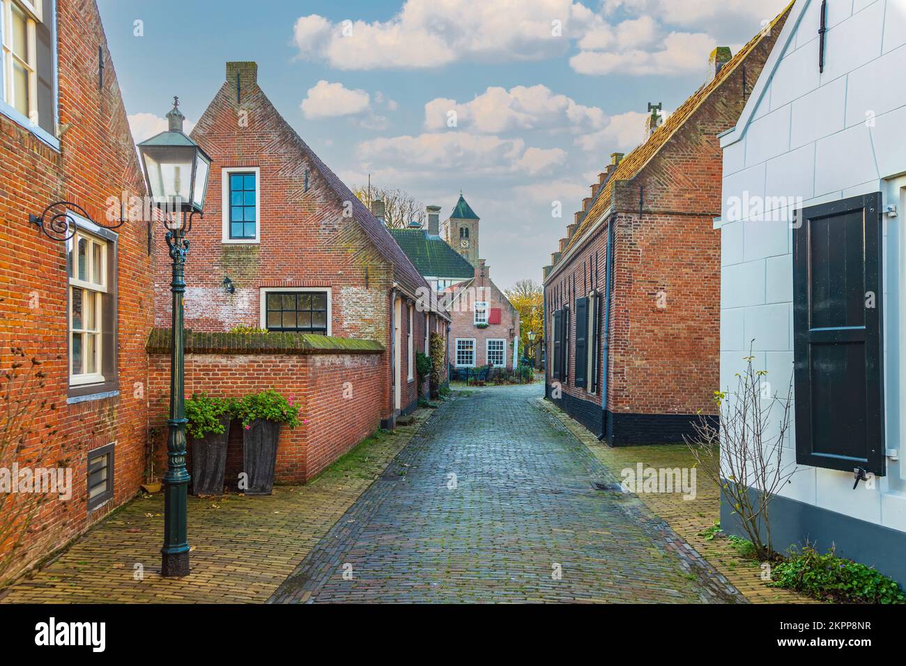 Blick auf die Straße bei Sonnenaufgang von historischen Häusern in der Hoofdbuurtstraat in Oud Velsen in der niederländischen Provinz Nordholland mit Engelmunduskerk Stockfoto