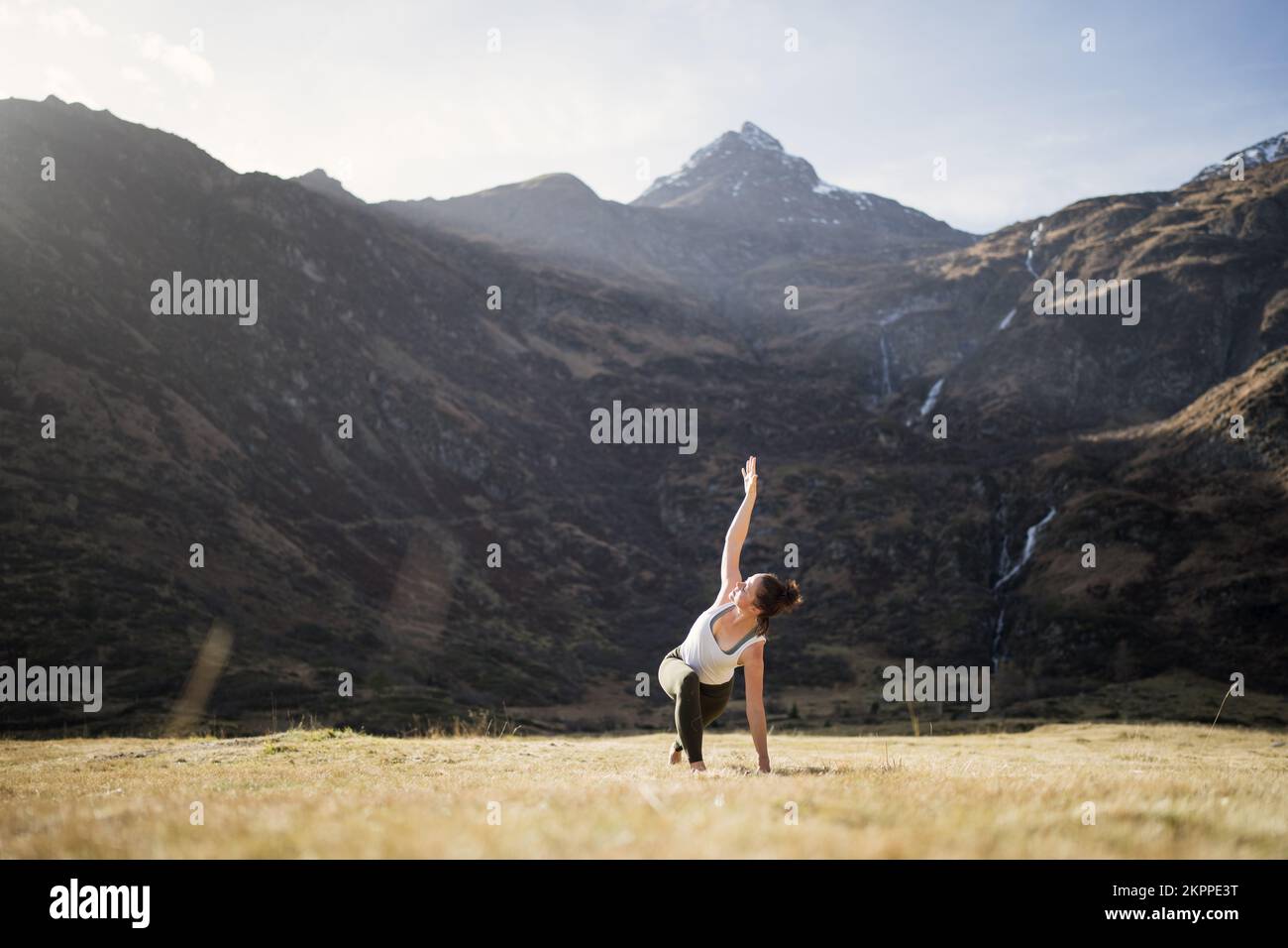 Frau, die Yoga-Dreieck-Pose mit gebeugtem Knie auf einer alpinen Wiese macht, Gastein, Österreich Stockfoto