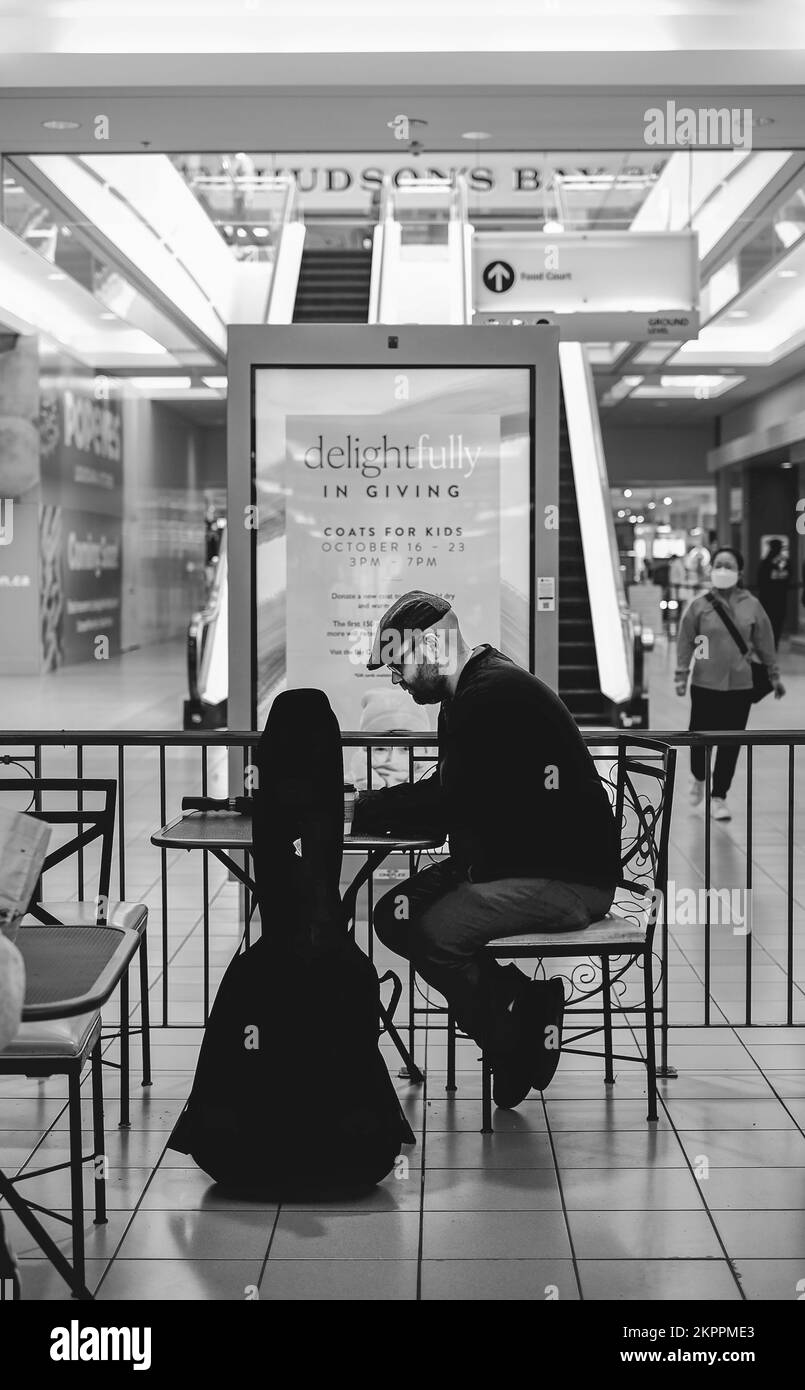 Geschäftsessen im Einkaufszentrum. Ein Mann sitzt allein im Café am Food Court in einem Einkaufszentrum. Editorial, Selektivfokus-Richmond BC Kanada-Oktober 2 Stockfoto