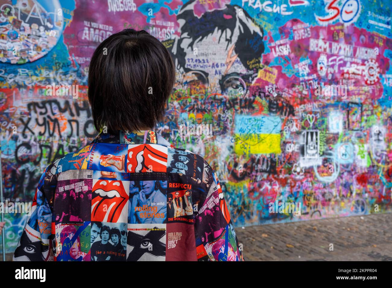 Prag, Tschechische Republik - 4. September 2022: Mann mit farbenfrohem Hemd, der auf die Lennon-Mauer schaut Stockfoto
