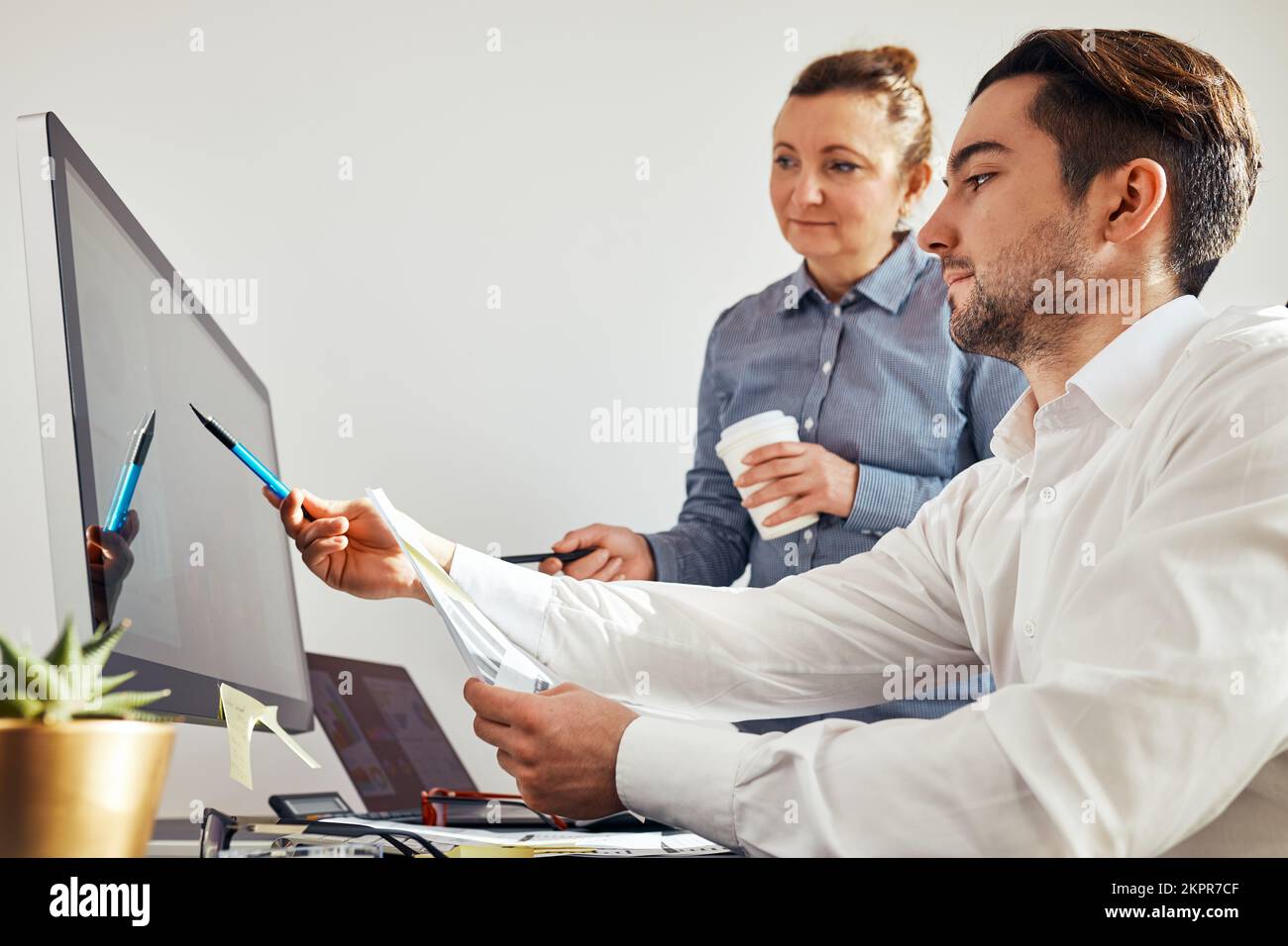 Zwei Geschäftsleute diskutieren Finanzdaten am Computer. Geschäftsfrau, die mit einem männlichen Kollegen im Büro zusammenarbeitet. Menschen Unternehmer arbeiten mit char Stockfoto