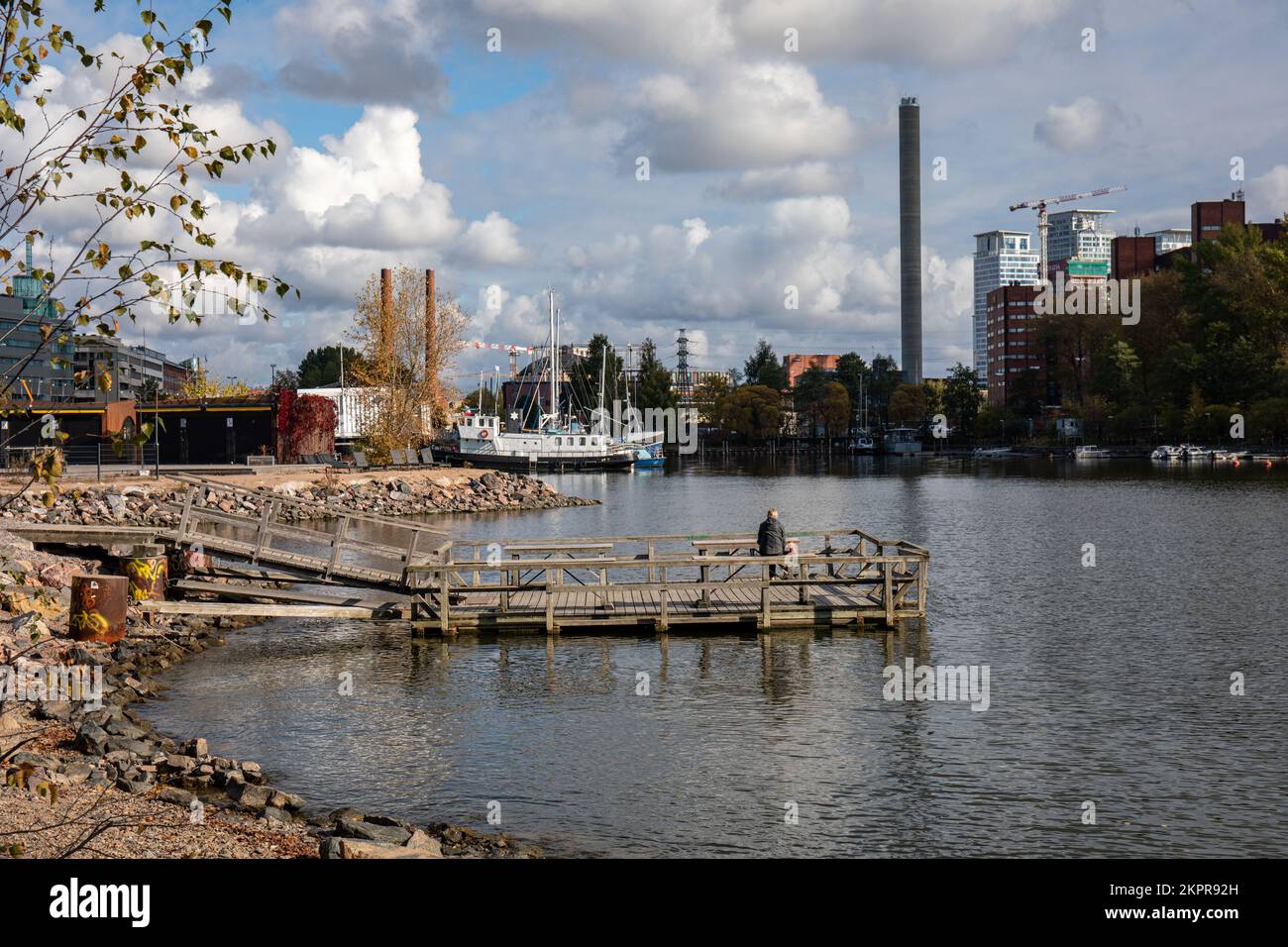 Person, die allein auf dem Teppichwaschpier in Sörnäinen waterfornt, Helsinki, Finnland sitzt Stockfoto