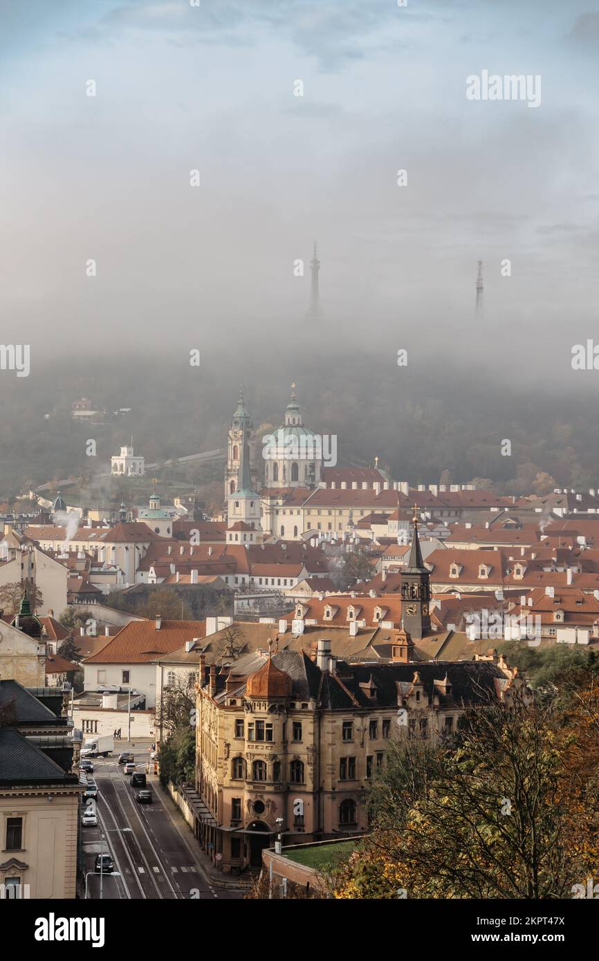 Prag Panorama mit historischen Gebäuden im nebligen Herbstmorgen, Tschechische Republik. Blick auf die Nikolaikirche und den Petrinturm im Nebel. Unglaubliche EUR Stockfoto