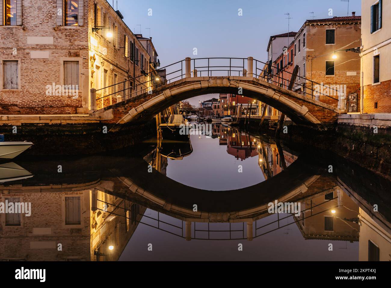 Wasserkanal, Brücke in der Dämmerung, Venedig, Italien. Typischer Bootstransport, venezianische Reise, städtische Szene. Wassertransport. Beliebtes Touristenziel. Romantisch Stockfoto