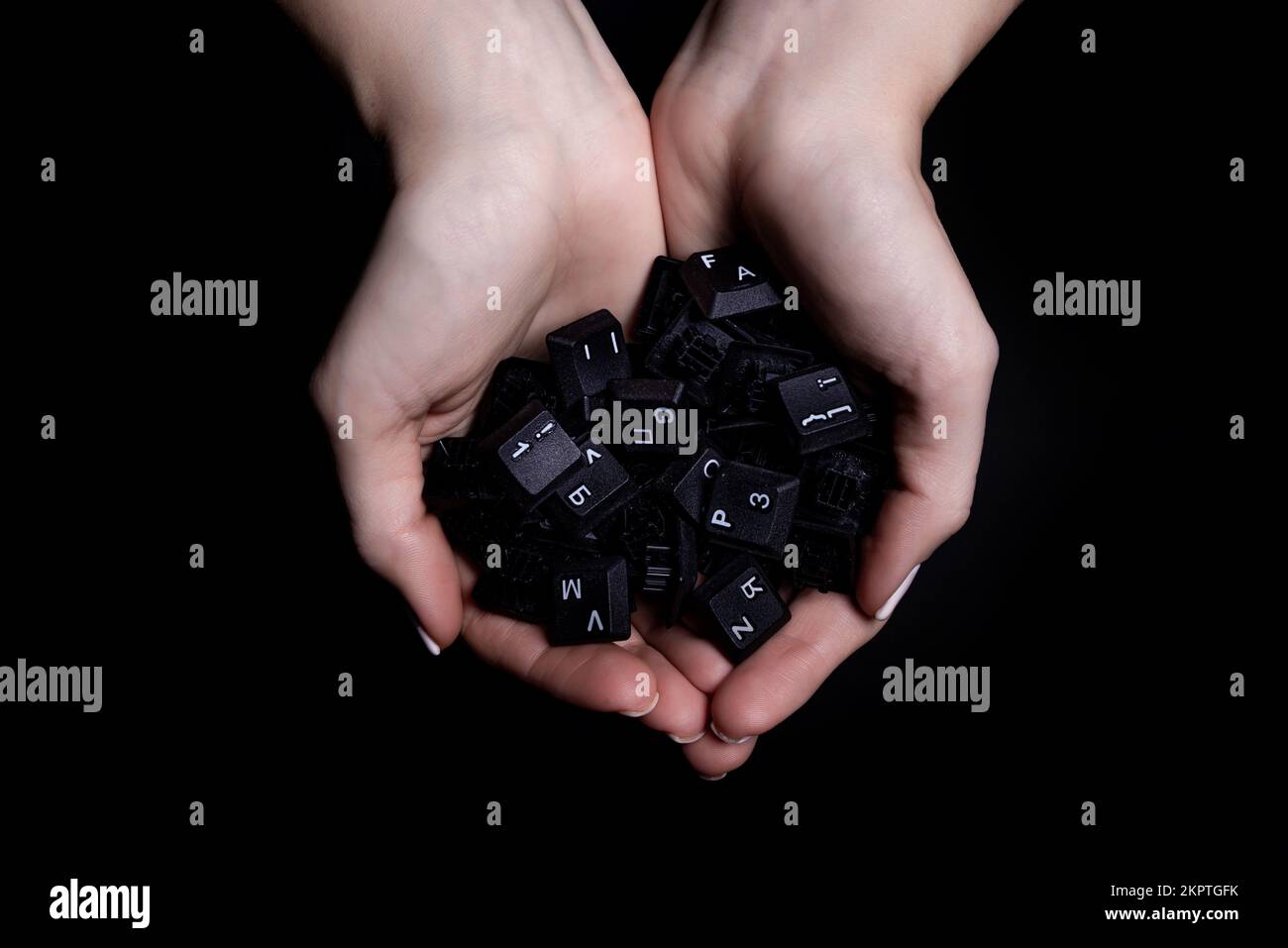 Weibliche Hände, die Tastaturtasten auf schwarzem Hintergrund isoliert halten, Ansicht von oben Stockfoto