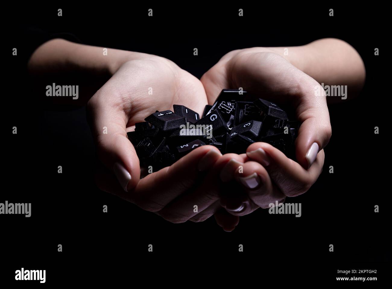 Weibliche Hände, die Tastaturtasten auf schwarzem Hintergrund isoliert halten, Ansicht von oben Stockfoto
