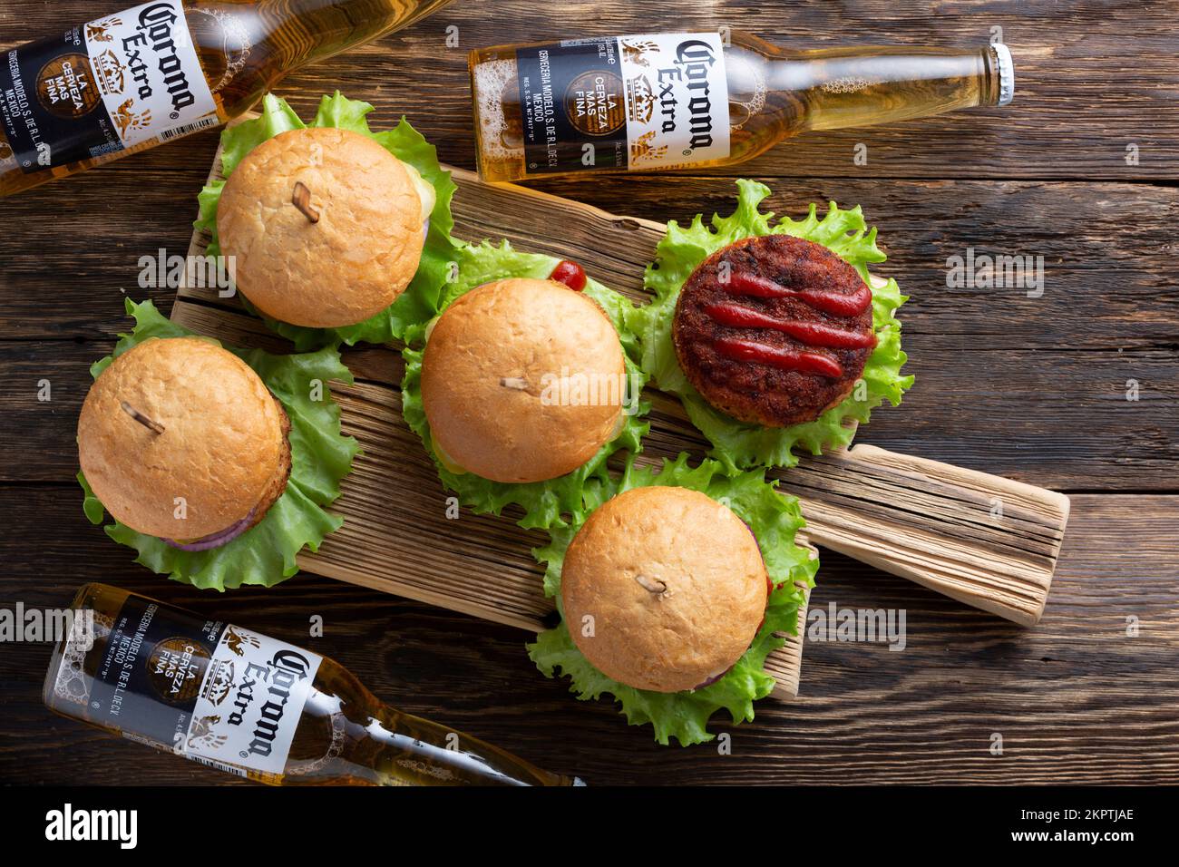 30.06.2022; Berlin; Deutschland; Korona-Bier und frische leckere Burger mit saftigen Fleischpasteten; Ketchup und Kräuter auf einem hölzernen Vintage-Tisch; Draufsicht; Resta Stockfoto