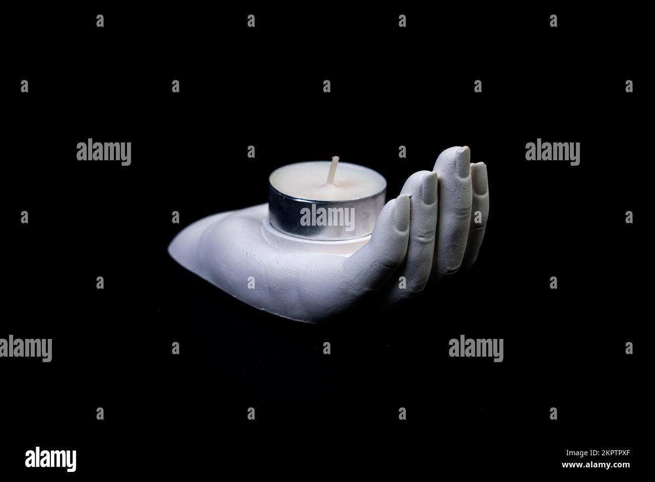 Kerzenhalter in Form einer Gipshand mit Kerzen, ein Gipskerzenhalter in Form eines Steins. Teekerze. Kerzenhalter im Innenraum mit Ihrem Au Stockfoto