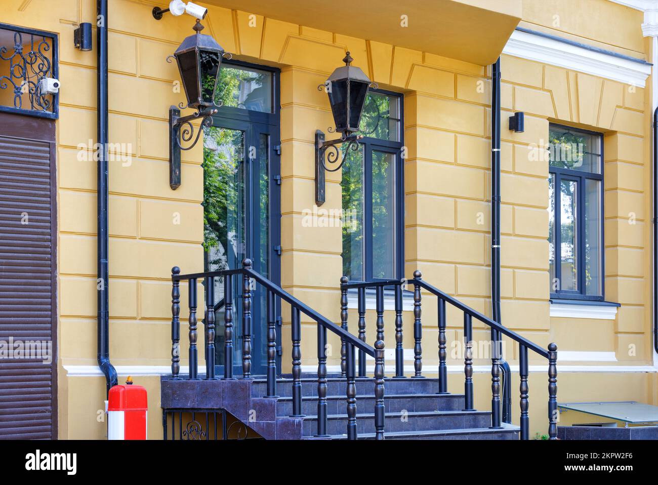 Ein Teil eines modernen, wunderschönen Eingangs eines Hauses mit Laternen, großen Fenstern und Eingangstüren mit Elementen des alten Stils. Stockfoto