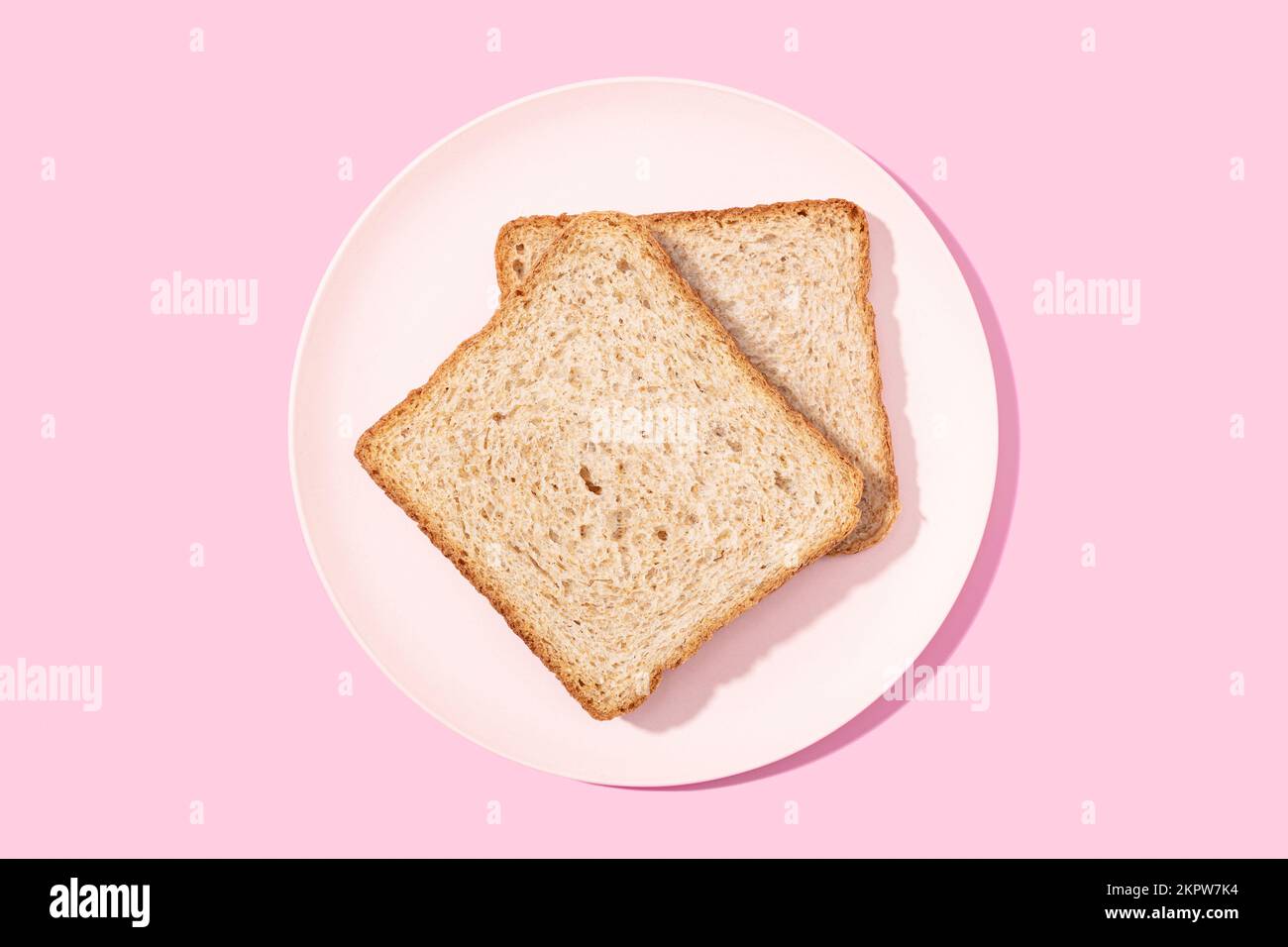 Vollkorn-Sandwich-Brot auf einem Teller mit pinkfarbenem Hintergrund. Flach verlegt Stockfoto