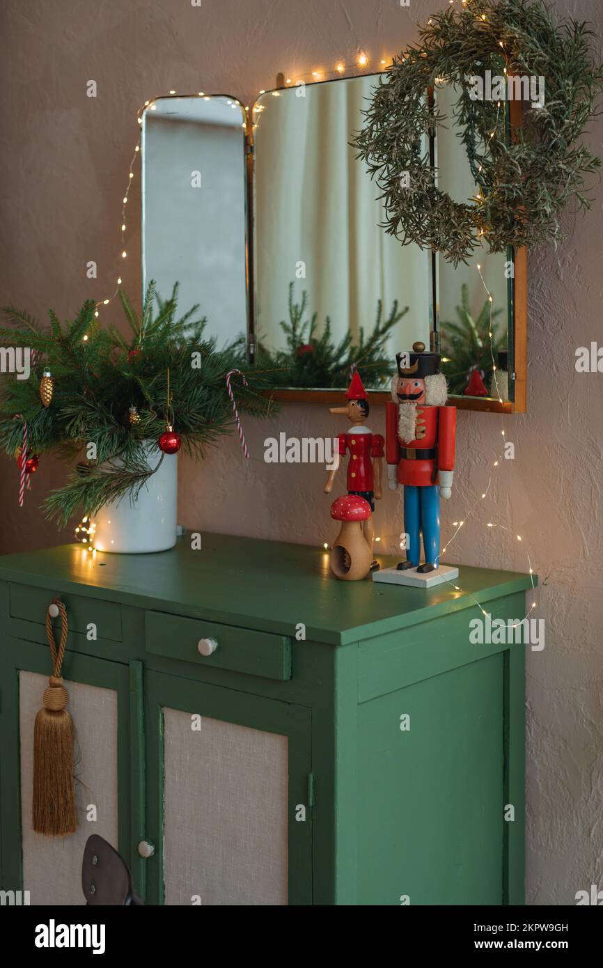 Spiegel über einem Sideboard in einem Wohnzimmer, dekoriert mit Lichterketten, Kranz, Weihnachtsdekorationen und Ornamenten Stockfoto