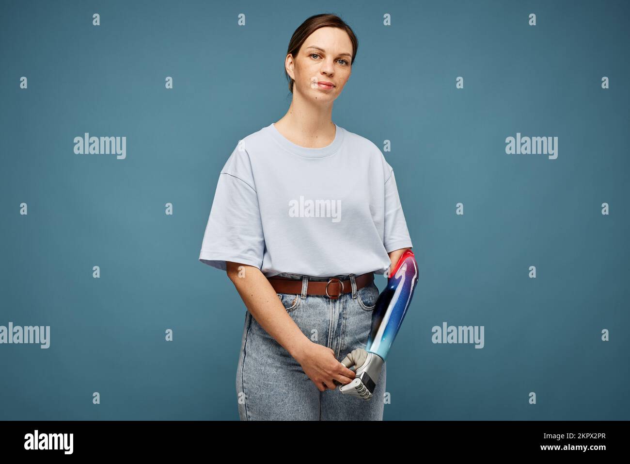 Porträt einer unlächelnden jungen Frau mit Armprothesen vor dem grauen Hintergrund Stockfoto