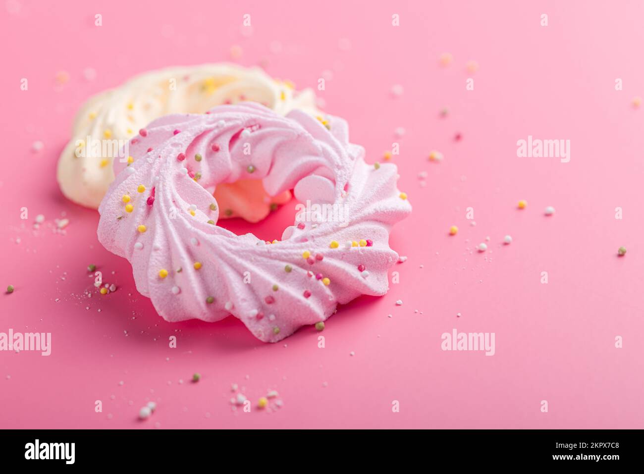 Verschiedene Farben Baiser mit Streuseln auf dem pinkfarbenen Tisch. Stockfoto